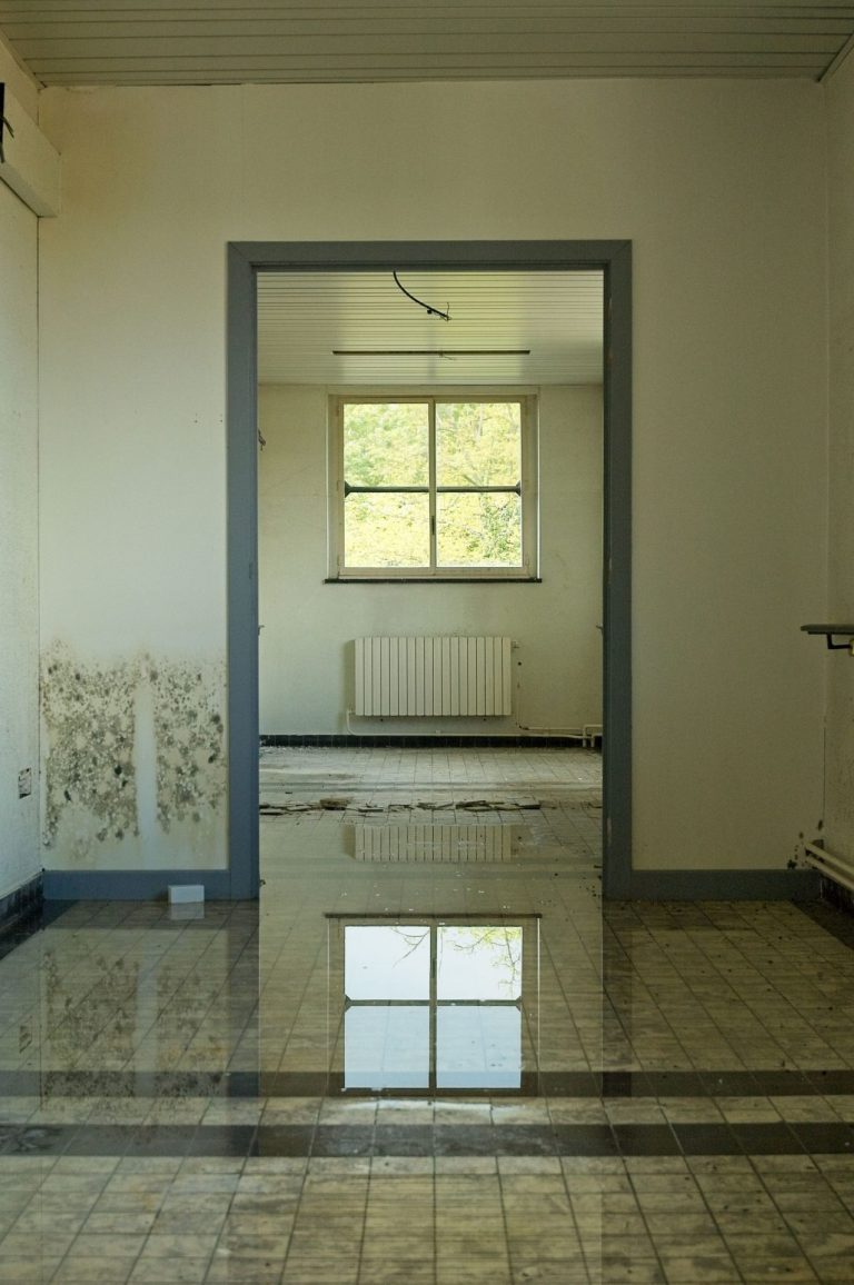 Raum mit nassem Boden und Feuchtigkeitsschäden an der Wand