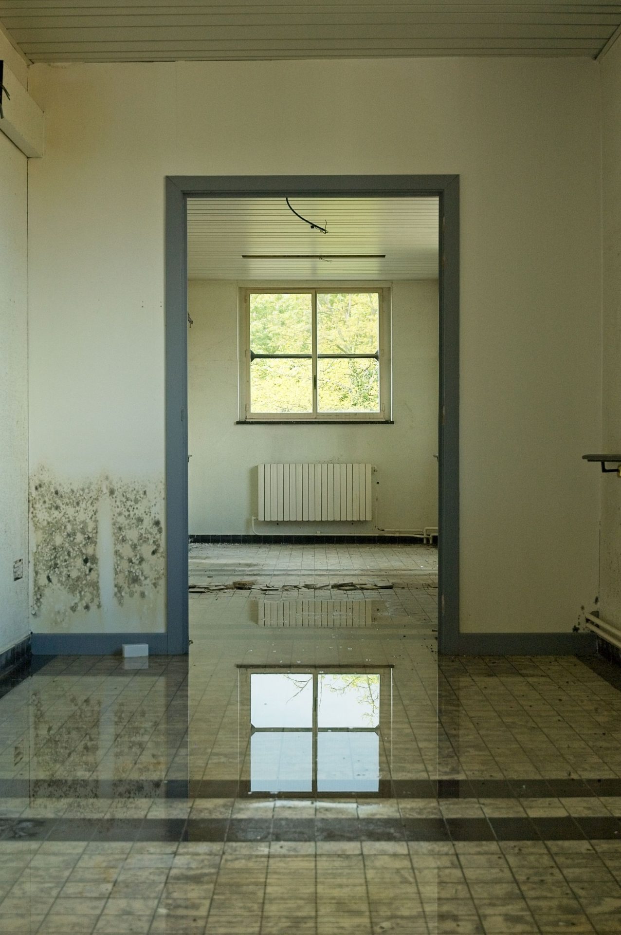 Raum mit nassem Boden und Feuchtigkeitsschäden an der Wand