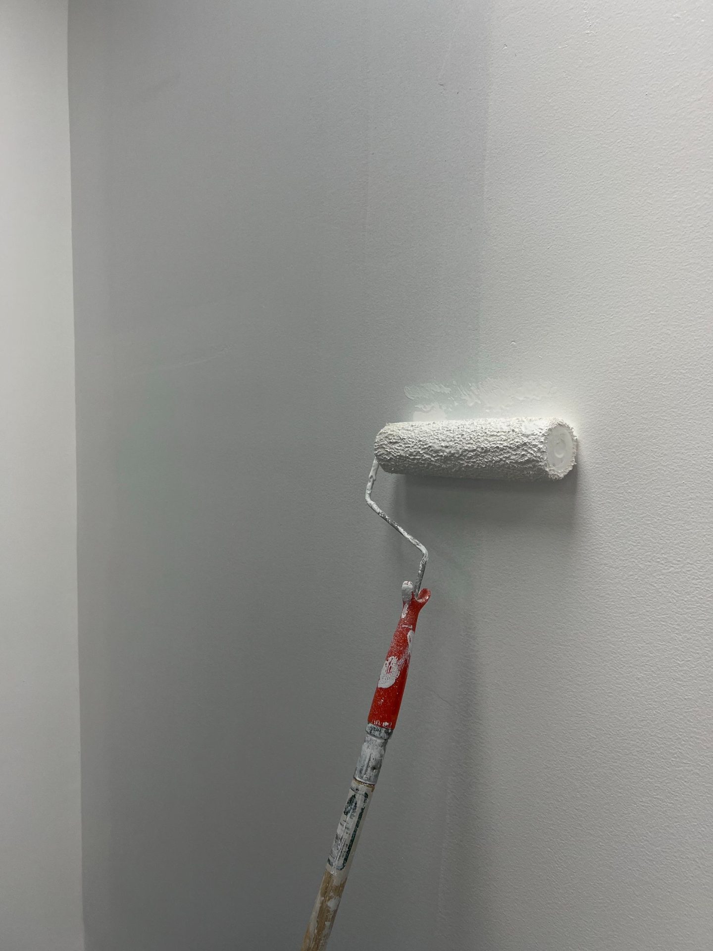 Frisch gestrichene weisse Wand mit Farbroller