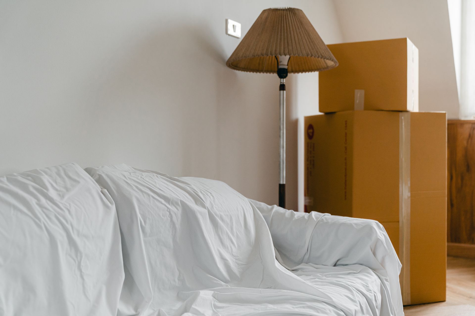 Abgedecktes Sofa und Umzugskartons in einer Wohnung
