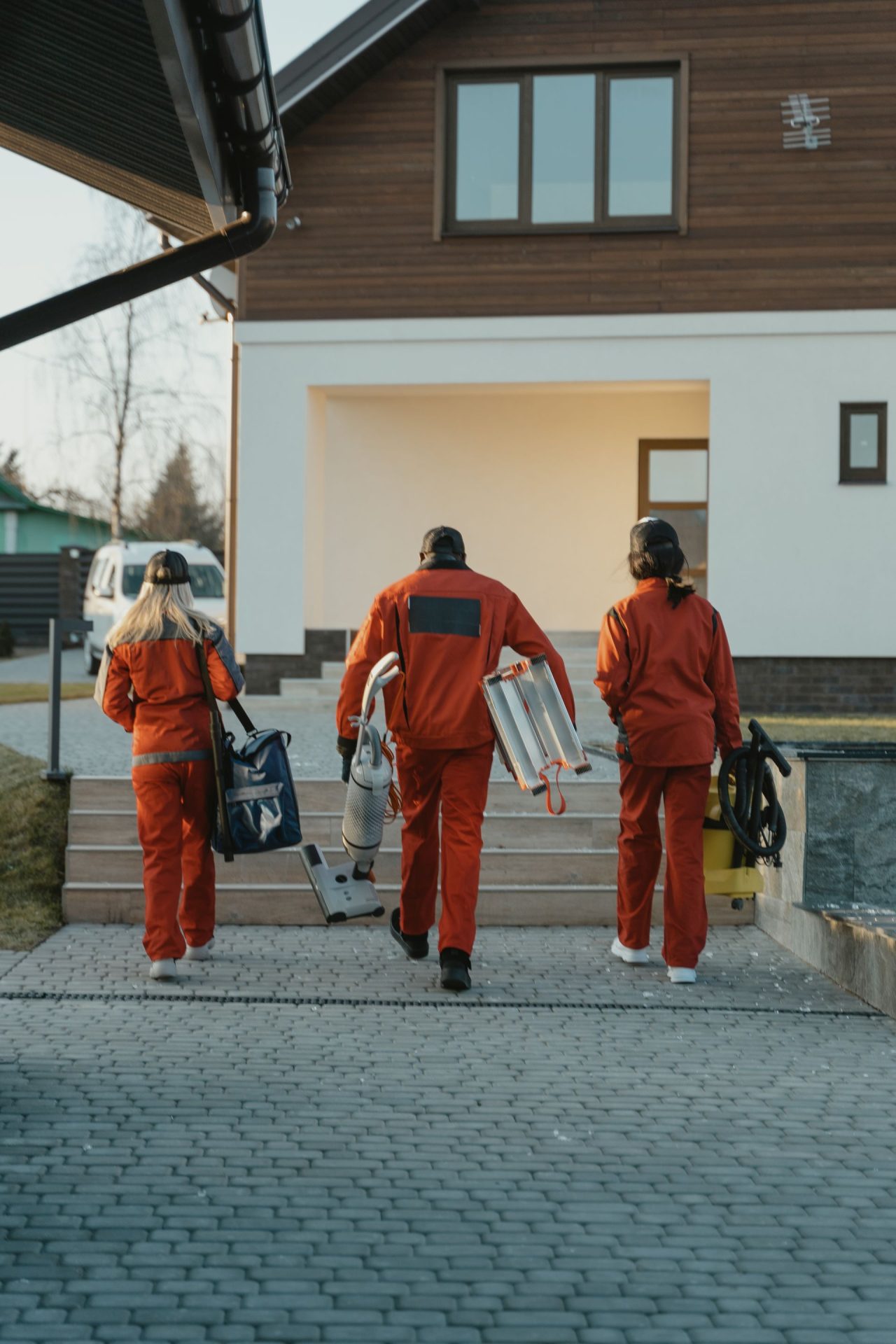Team mit Reinigungsgeräten auf dem Weg zum Hauseingang